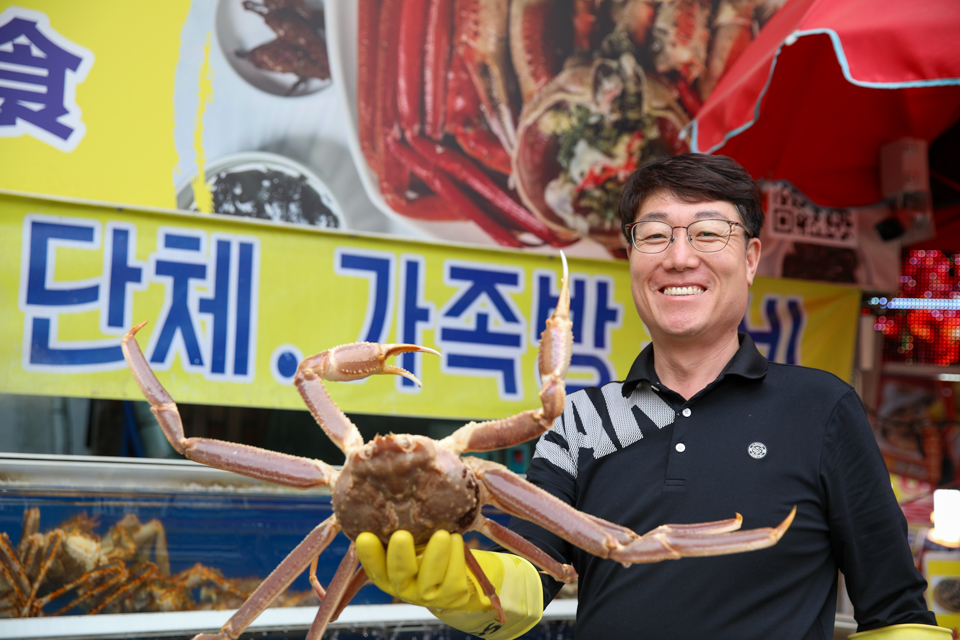 기장 청해왕대게 정영진 대표가 매장 앞에서 활대게를 직접 들고 있는 모습 — 부산 대게 맛집