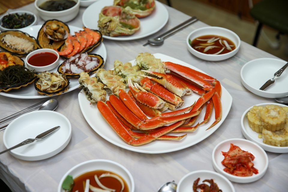 Live snow crabs stacked in the tiers of a storefront tank with water flowing through