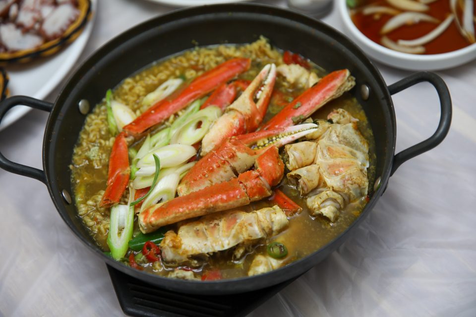 A snow crab spread with side dishes laid out for two people sitting across from each other
