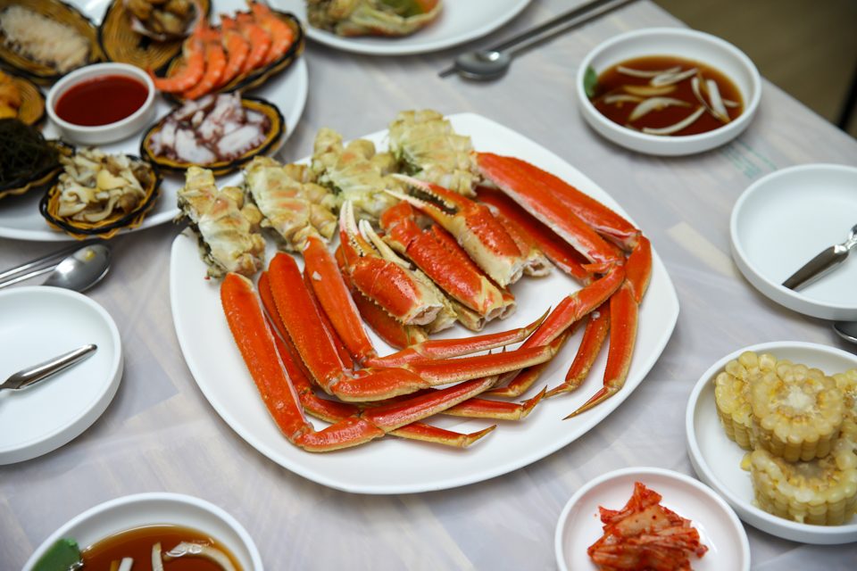 대게 다리 접시를 가운데 두고 여러 곁들임 그릇이 상 위에 둘러 놓인 구성
