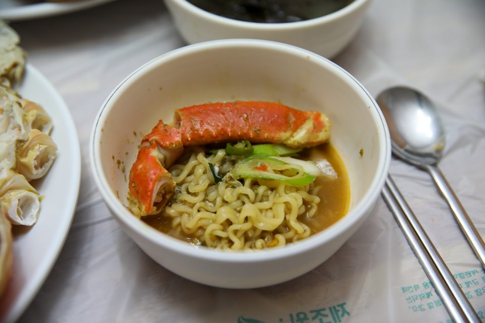 라면 위에 붉은 대게 다리를 올려 국물과 함께 담아낸 그릇