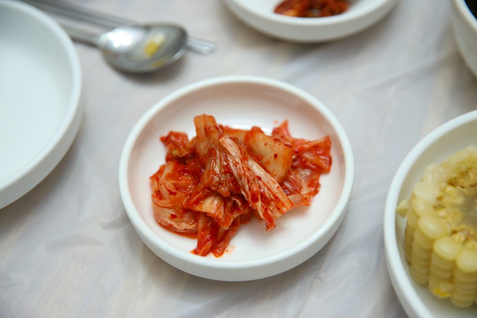 흰 접시에 담긴 김치와 노란 단무지가 놓인 기본 반찬