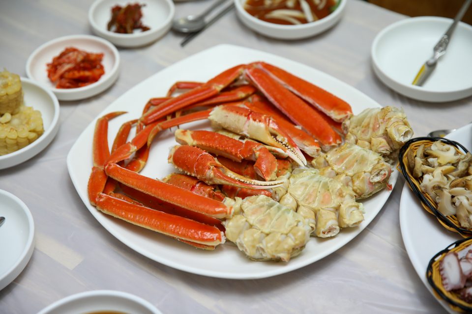 겹쳐 쌓인 다리 사이로 김이 오르는 대게 접시