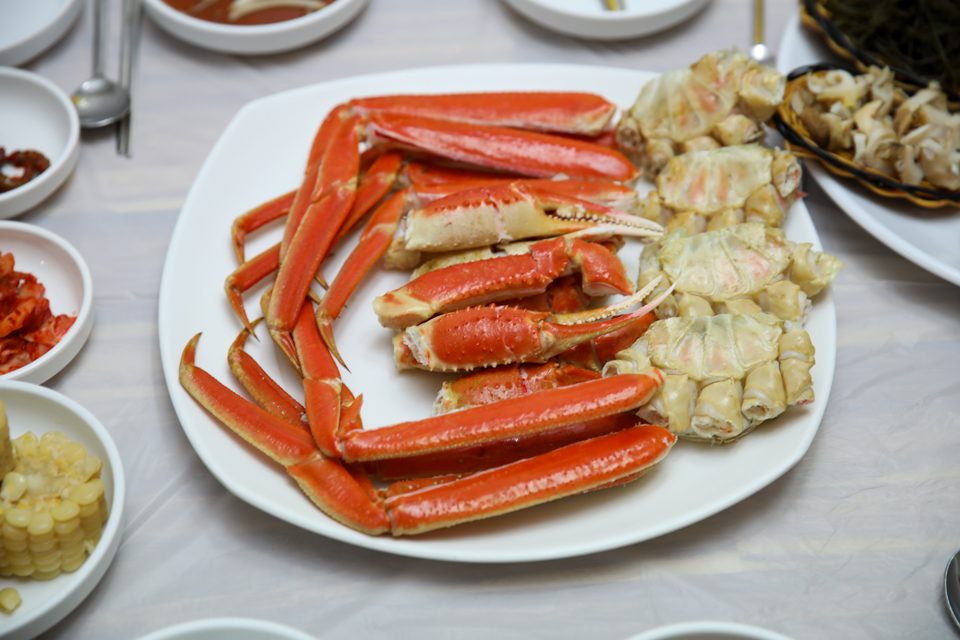 접시에 수북이 오른 찐 대게 다리와 곁들임 상